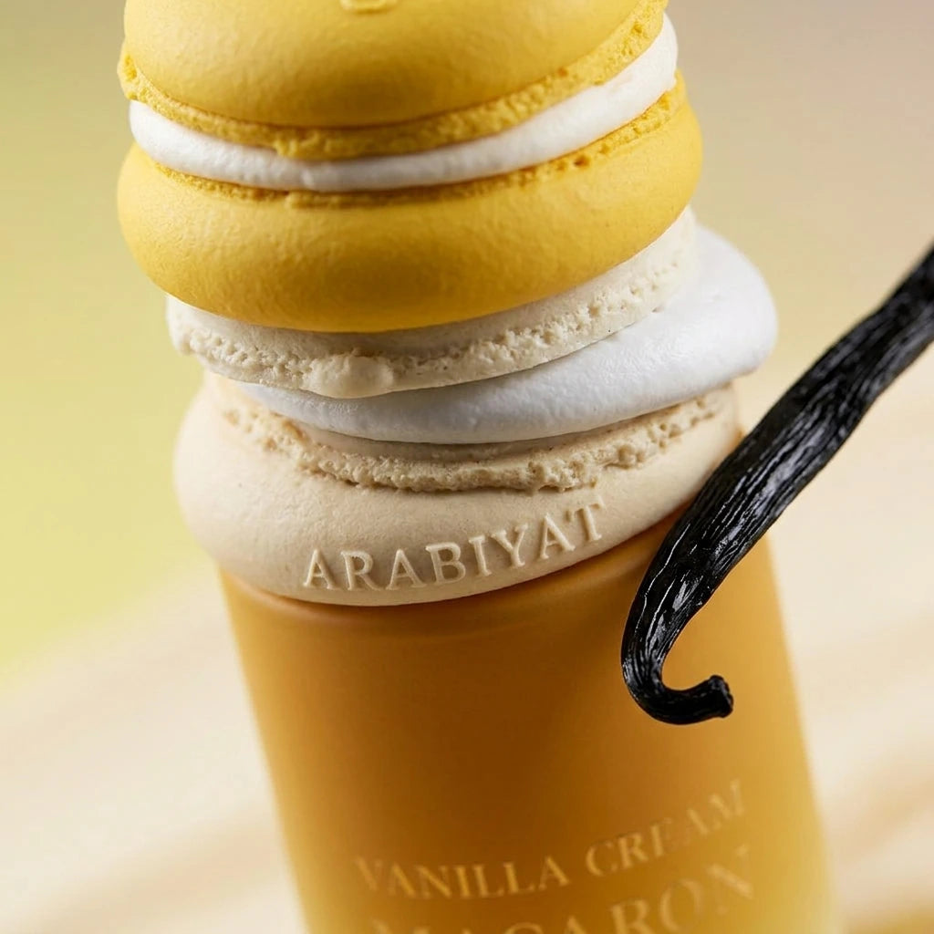 Angle : Gros plan macro serré, angle à $45^\circ$ centré sur l'incroyable capuchon en forme de macarons empilés.Scène : Focus absolu sur les textures mates et croustillantes des macarons du flacon de l'image image_8ba980.jpg. L'éclairage de studio (boîte à lumière focalisée de profil) met en relief les couches de ganache blanche texturée du bouchon. Juste à côté, une véritable gousse de vanille noire et luisante est artistiquement disposée pour capter de légers reflets.Fond : Arrière-plan flou de studio (bo