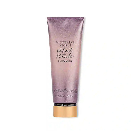 Victoria's Secret Velvet Petals Shimmer Lotion Parfumée bottle with floral design and golden accents, emitting a soft, luminous glow.